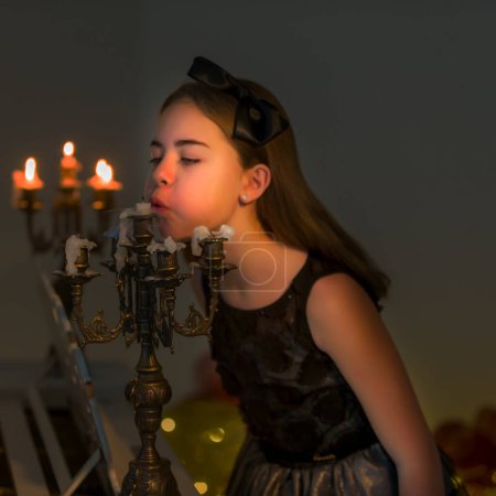 Foto de Encantadora chica preadolescente soplando velas en la araña vintage. - Imagen libre de derechos