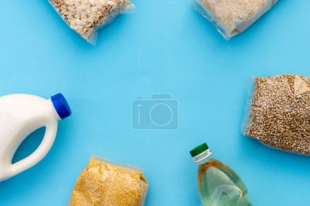 Foto de Abastecimiento. Gachas crudas, cereales, leche y aceite vegetal en la mesa azul. Copia del espacio, plana. Seguridad alimentaria para los pobres - Imagen libre de derechos
