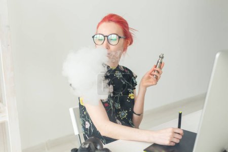 Photo for "graphic designer concept - Female graphic designer working on computer while using graphic tablet at desk in the office and smoking a vape" - Royalty Free Image