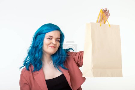 Foto de "Venta, shopaholic y concepto de consumidor - hermosa chica con el pelo azul de pie con bolsas de compras sobre fondo blanco
" - Imagen libre de derechos