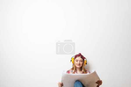 Foto de "Chica feliz en los auriculares de protección sentado" - Imagen libre de derechos