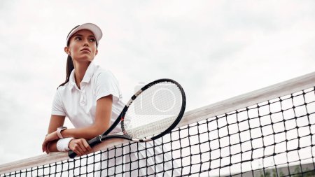 Photo for "Young tennis player standing on a court and holding a racket." - Royalty Free Image
