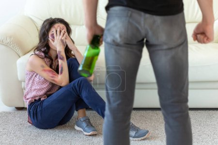 Téléchargez les photos : "violence domestique, alcoolisme et abus concept - homme ivre avec bouteille abusant de sa femme assise sur le sol
" - en image libre de droit