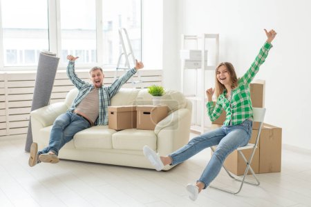 Photo for Positive cheerful couple rejoices in moving their new apartment sitting in the living room with their belongings. Concept of housewarming and mortgages for a young family. - Royalty Free Image