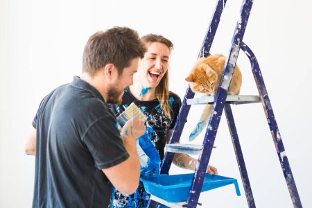 Téléchargez les photos : Personnes, concept de redécoration et de rénovation portrait de couple avec chat versez de la peinture - en image libre de droit