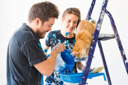 Téléchargez les photos : "Concept de personnes, rénovation et réparation portrait de couple heureux avec chat verser de la peinture
" - en image libre de droit