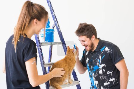 Téléchargez les photos : Personnes, concept de redécoration et de rénovation portrait de couple avec chat versez de la peinture - en image libre de droit