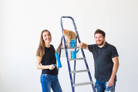 Téléchargez les photos : Personnes, redécoration et concept de relation - Jeune couple drôle avec chat faisant de la rénovation dans un nouvel appartement - en image libre de droit
