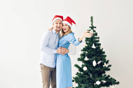 Téléchargez les photos : "Vacances d'hiver et concept familial - Joyeux jeune couple près du sapin de Noël à la maison
" - en image libre de droit
