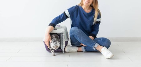 Foto de "Mujer atractiva positiva y hermoso gato Fold gris escocés en su nuevo apartamento después de la mudanza. El calentamiento de la casa y el concepto de mascotas
." - Imagen libre de derechos