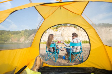 Téléchargez les photos : Les gens, le tourisme et la nature concept - Couple mignon assis près de tente jaune - en image libre de droit