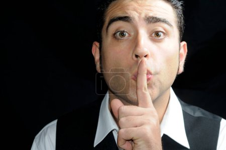 Photo for "Man asking for silence with his finger over his mouth" - Royalty Free Image