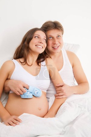 Foto de "happy young pregnant woman with husband on bed" - Imagen libre de derechos