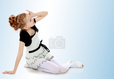 Photo for "Girl sitting on the floor leaning on hand and looking to the sid" - Royalty Free Image
