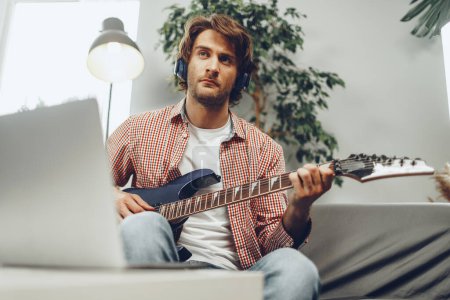 Photo for Man playing electric guitar and recording music into laptop - Royalty Free Image