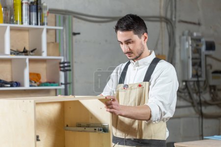 Photo for Furniture factory, Small-Sized Companies and people concept - Young worker works in a factory for the production of furniture - Royalty Free Image