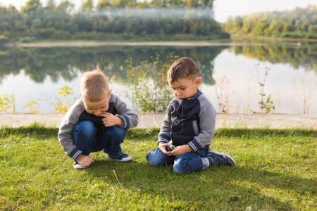 Téléchargez les photos : Les enfants et la nature concept - Deux frères assis sur l'herbe sur fond de nature - en image libre de droit
