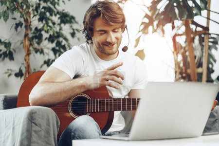 Photo for "Young man watching guitar tutorial on his laptop" - Royalty Free Image