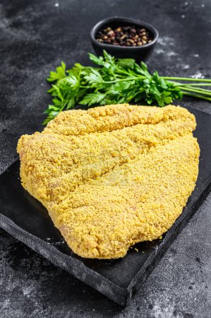 Photo for Raw large Viennese schnitzel on a cutting board. Black background. Top view - Royalty Free Image