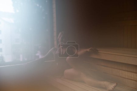 Téléchargez les photos : "Femme assise sur le banc dans le sauna" - en image libre de droit