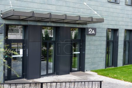 Téléchargez les photos : La porte d'entrée d'un immeuble de bureaux, reflétant les bâtiments dans le verre - en image libre de droit