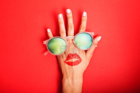 Foto de "Gafas de sol de mano de mujer sobre fondo brillante, concepto de vacaciones de verano cosmético
" - Imagen libre de derechos