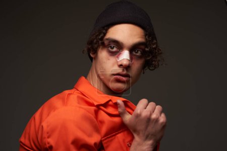 Foto de Hombre con la nariz rota moretones bajo los ojos naranja camisa crimen - Imagen libre de derechos