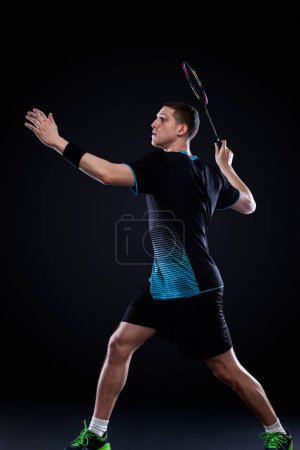Téléchargez les photos : Joueur de badminton en tenue de sport avec raquette et volant sur fond noir
. - en image libre de droit