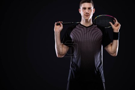 Téléchargez les photos : Joueur de badminton en tenue de sport avec raquette et volant sur fond noir. Sports individuels. Loisirs sportifs
. - en image libre de droit