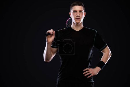 Téléchargez les photos : Joueur de badminton en tenue de sport avec raquette et volant sur fond noir
. - en image libre de droit