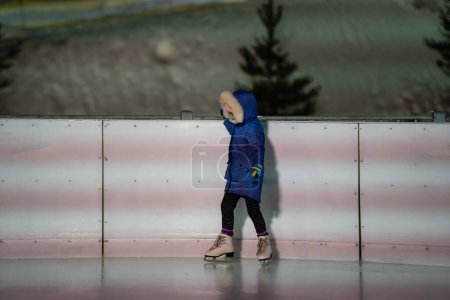 Téléchargez les photos : Petite fille apprenant à patiner à la patinoire - en image libre de droit