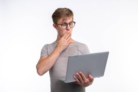 Photo for People and education concept - Shocked man holding a laptop over white background - Royalty Free Image
