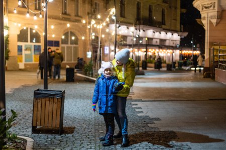 Foto de Madre e hija caminan por la ciudad en Navidad y Año Nuevo - Imagen libre de derechos