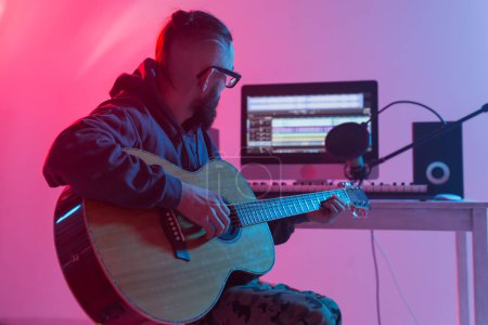 Photo for Create music and a recording studio concept - Bearded man guitarist recording electric guitar track in home studio - Royalty Free Image
