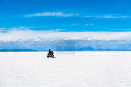Photo for "Sunshine scenery of Salar de Uyuni in Bolivia with biker riding over" - Royalty Free Image