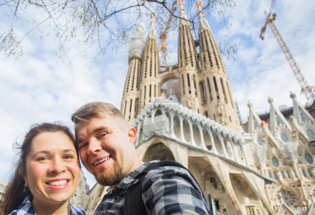 Foto de "Pareja feliz haciendo foto selfie frente a la famosa catedral católica de la Sagrada Familia. Viajar en Barcelona" - Imagen libre de derechos