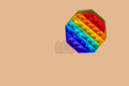Téléchargez les photos : Populaire jouet anti-stress multicolore pop-it repose sur un fond orange - en image libre de droit