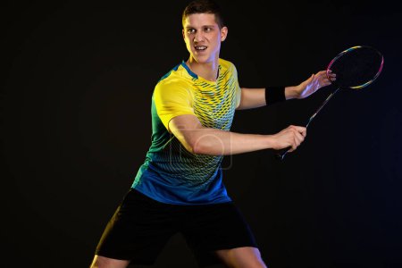 Photo for Badminton player in sportswear with racket and shuttlecock on black background. - Royalty Free Image