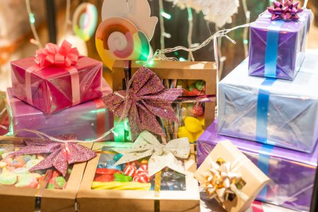 Photo for "Stylish christmas gift boxes with ribbons and bows in window store in evening. Christmas festive street decor, holiday winter shopping and sales. Merry Christmas." - Royalty Free Image
