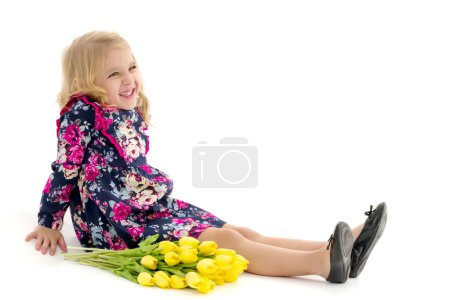 Photo for A little girl is lying on the floor with a bouquet of tulips. - Royalty Free Image