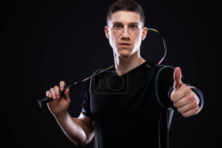 Photo for Badminton player in sportswear with racket and shuttlecock on black background. Emotional sport portrait with man which show sight thumbs up and good luck. - Royalty Free Image
