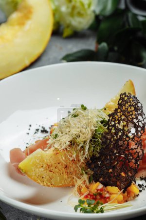 Téléchargez les photos : Melon cuit au four avec parmesan et jamon sur une assiette blanche - en image libre de droit