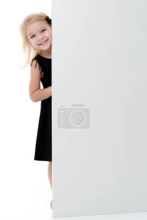 Téléchargez les photos : Une petite fille regarde derrière une bannière vide. - en image libre de droit