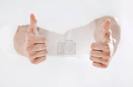 Foto de Hombre rompiendo la pared de papel y mostrando los pulgares hacia arriba
. - Imagen libre de derechos