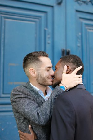 Photo for Caucasian man kissing afro american boy in door background. - Royalty Free Image