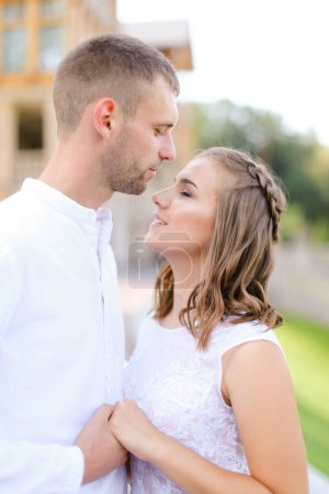 Photo for "Groom kissing bride and holding hands outside." - Royalty Free Image