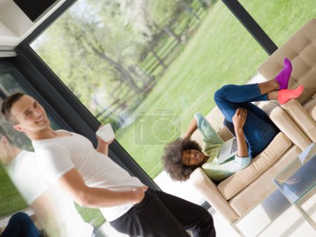 Foto de Pareja multiétnica relajarse en casa con ordenadores portátiles - Imagen libre de derechos