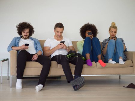 Foto de Grupo multiétnico de jóvenes mirando fijamente el teléfono inteligente - Imagen libre de derechos
