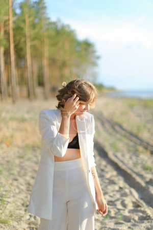 Photo for Pretty girl walking on sand beach and wearing white clothes. - Royalty Free Image