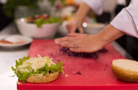 Téléchargez les photos : "chef cutting salad for burger" - en image libre de droit